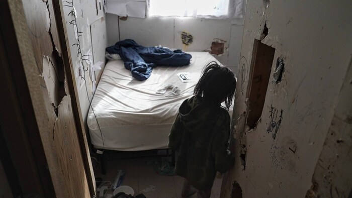 Un enfant entre dans une chambre dont les murs sont troués.