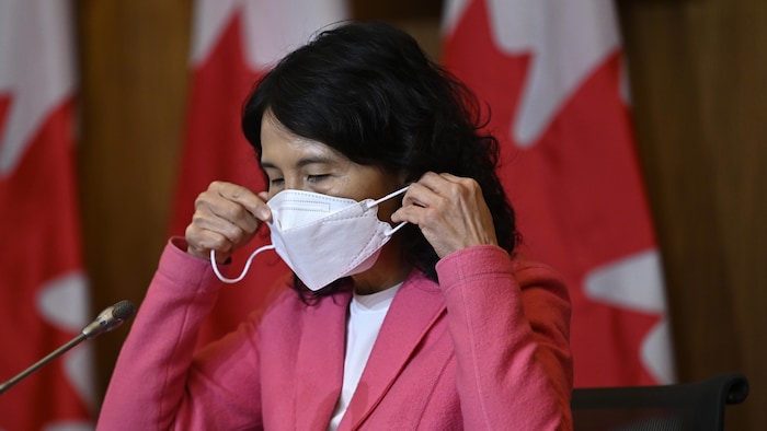 La docteure Theresa Tam mettant un masque sur son visage.
