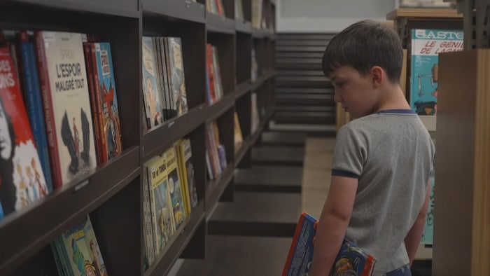 Thomas choisit des livres à la bibliothèque de Rouyn-Noranda.