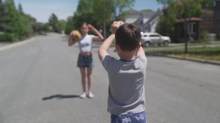 Thomas joue au ballon avec sa sœur dans la rue.