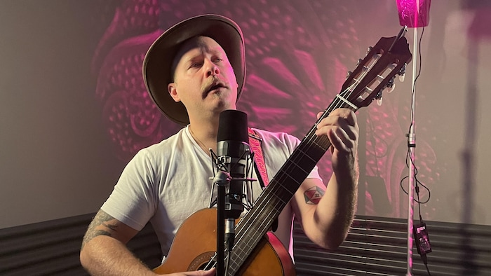 Thomas Chevalier chante en jouant de la guitare.