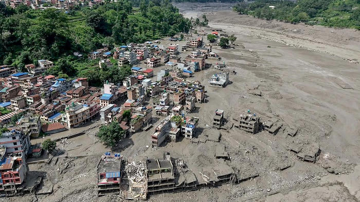 Vue aérienne de maisons partiellement submergées dans des eaux boueuses.