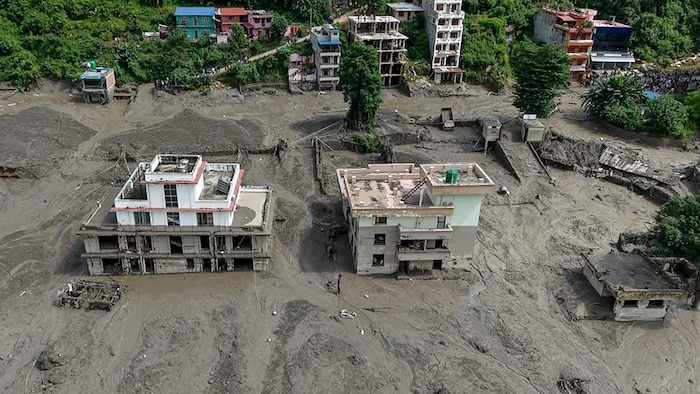 Des maisons sont partiellement submergées dans des eaux boueuses le long d’une rive après des crues soudaines à Trishuli Bazar, dans le district de Nuwakot au Népal, le 26 août 2026.