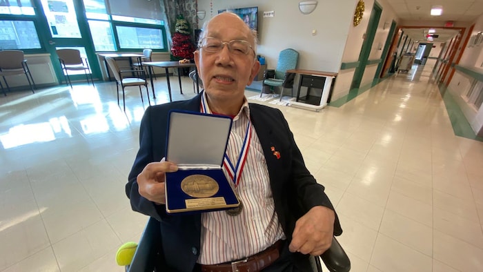 陈福添老人手拿魁北克政府颁发给该医院的国家议会勋章。