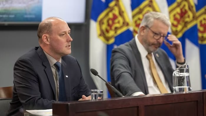 Les ministres Tim Halman et John Lohr assis lors d'une conférence de presse.