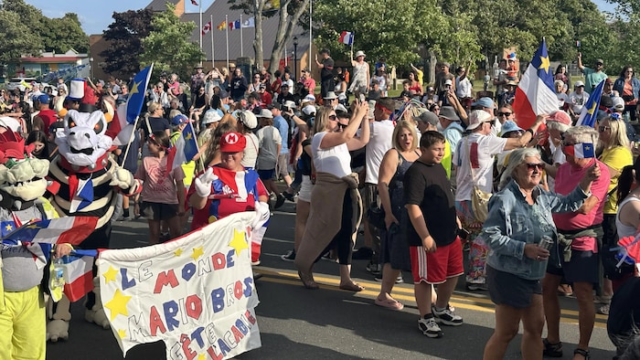 Dans un défilé, une femme est déguisée en Mario et deux autres festivaliers derrière sont costumés en Bowser.
