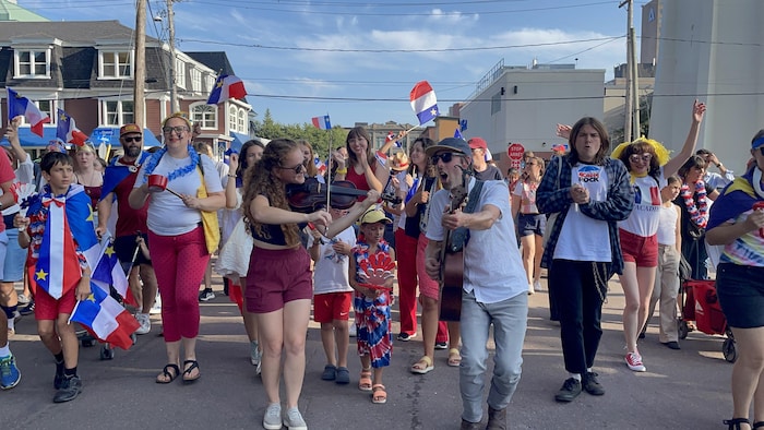 Des gens qui défilent au centre-ville de Moncton vêtus aux couleurs du drapeau acadien.