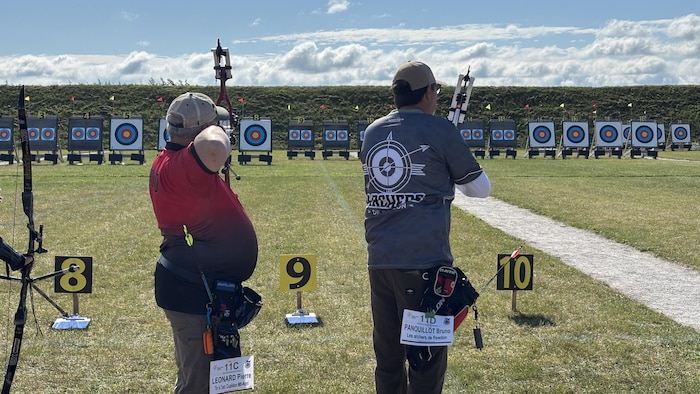 Two participants are preparing to uncheck their arrows towards targets.