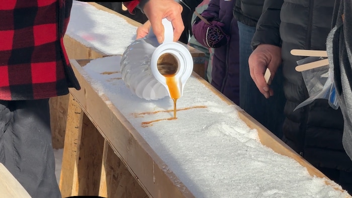 Un homme qui verse de l'érable sur de la neige.