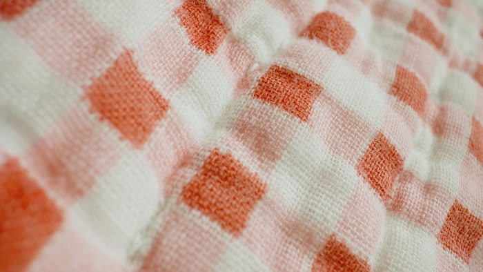 Plan très rapproché montrant le détail du tissage d'un tissu rouge et blanc.