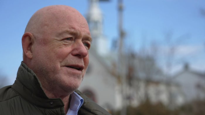 Un homme accorde une entrevue devant une église.