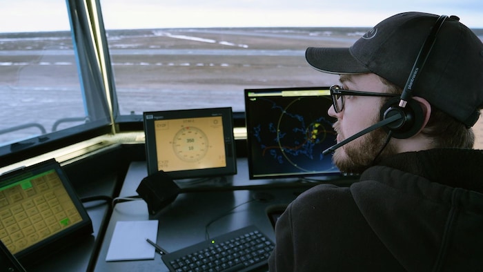 Un contrôleur aérien avec casque et micro, devant une fenêtre, le 25 avril 2024, à Yellowknife.