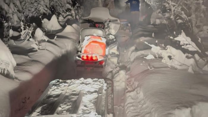 Des motoneiges sur une piste très enneigée durant la nuit.