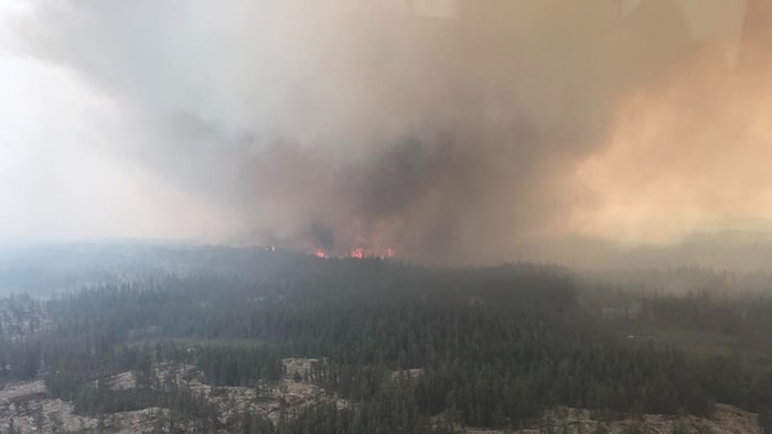 Vue aérienne d'une forêt avec un feu et beaucoup de fumée dans le ciel, le 21 juillet 2023, aux Territoires du Nord-Ouest.