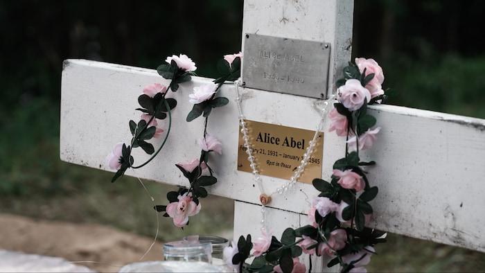 Une croix où sont superposées une vieille plaque et une plaque neuve.