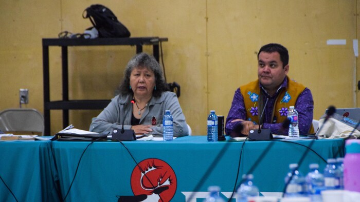 Elizabeth Biscaye assise devant un microphone, à côté d'une autre personne.