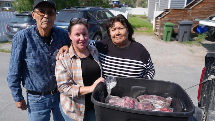 Trois personnes avec une boîte remplie de viande congelée.