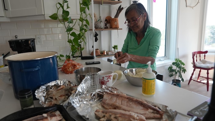 Une femme cuisine du poisson.