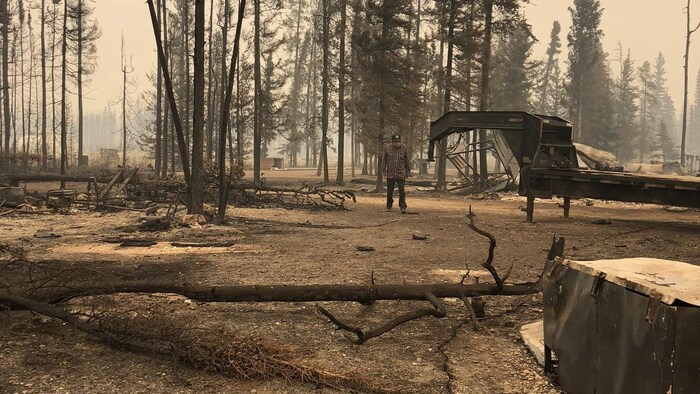 Un homme se tient debout dans une zone détruite par le feu de forêt, le 14 août 2023.