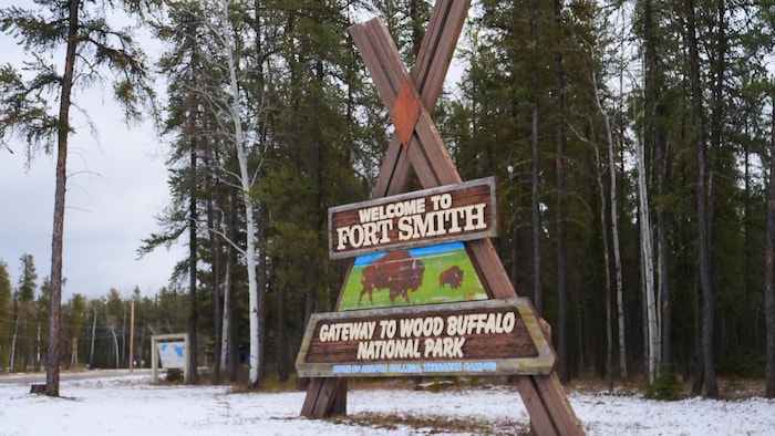 Enseigne en bordure d'une forêt indiquant, en anglais, welcome to Fort Smith Gateway to Wood Buffalo National Park, en octobre 2023.