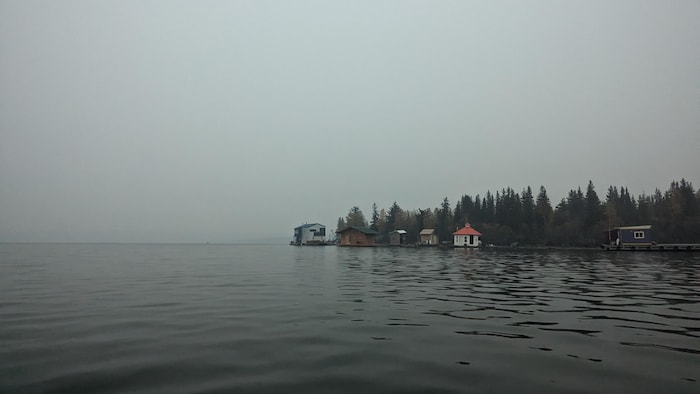 Des maisons au bord de l'eau sous un ciel gris.
