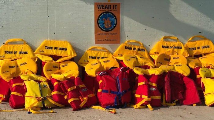 Des gilets de sauvetage empilés le long d'un mur.