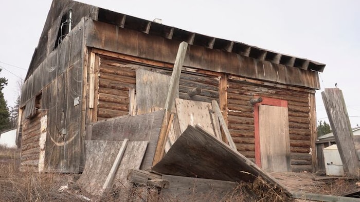 Une bâtisse en bois avec des plaque de bois entreposées autour.