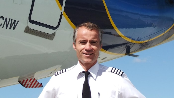 Le pilote Laval St-Germain pose devant un avion.