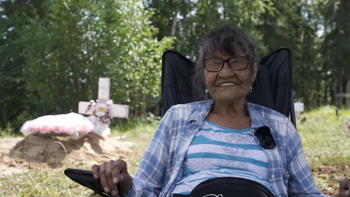 Thérèse Abel est assise sur une chaise au cimetière.
