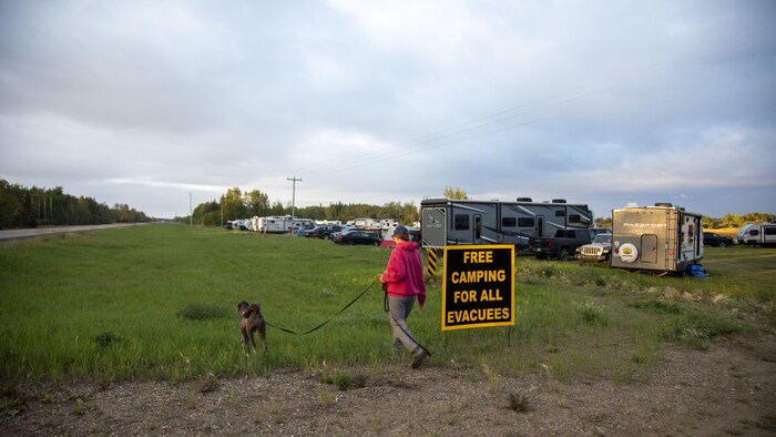 Une sinistée de Yellowknife fait marcher son chien autour de roulottes stationnées à High Level, en Alberta, le 18 août.