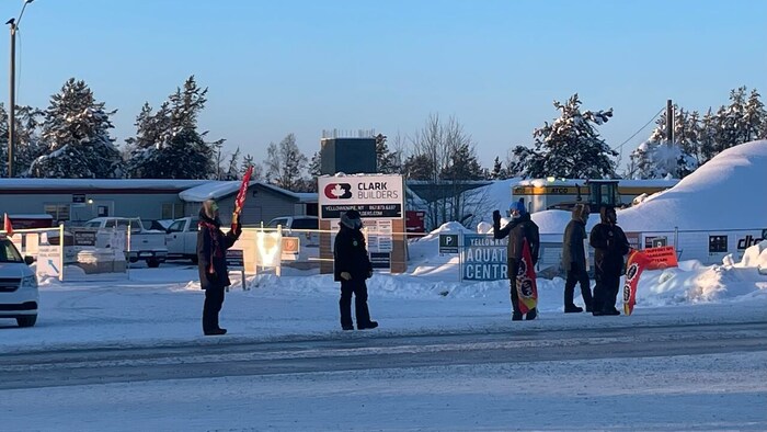 Cinq personnes dehors en hiver devant un chantier de construction à Yellowknife.