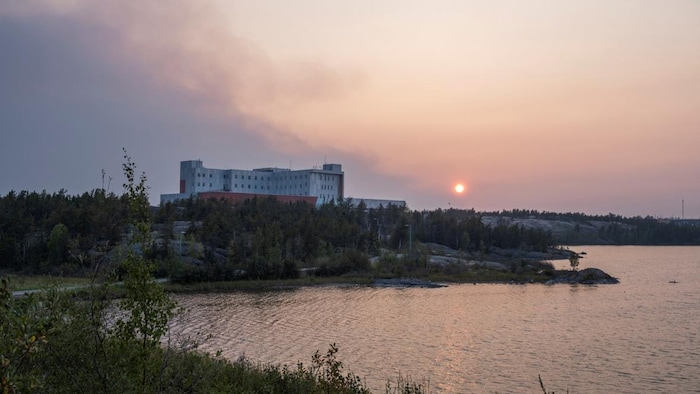 De la fumée surplombe l'hôpital territorial Stanton de Yellowknife, le 15 août 2023.
