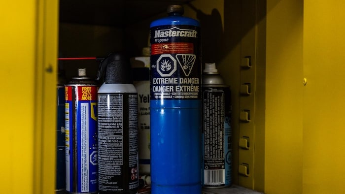 Des bonbonnes de propane et du diluant à peinture sur une étagère de métal.