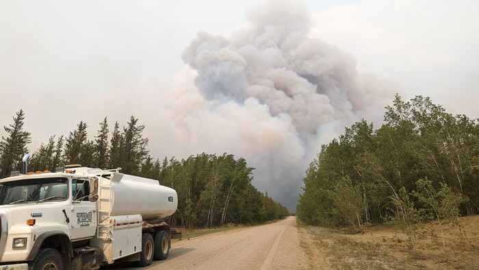 Route et camion avec nuage de fumée au loin, dans le parc national Wood Buffalo.