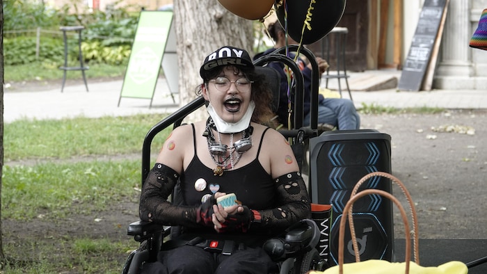 Une personne assise chantant avec la bouche ouverte et un sourire. 
