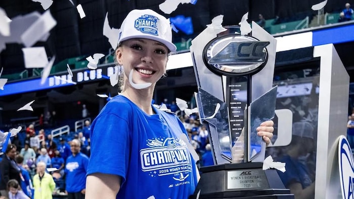 Une basketteuse pose pour la caméra avec un trophée.