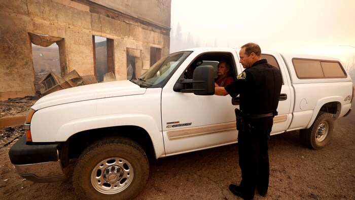 Todd Johns parle à un homme dans sa camionnette stationnée près d'un immeuble calciné.