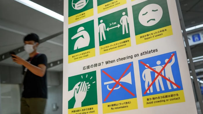 A man walks past a board showing COVID-19 countermeasures inside a venue next to the press centre in Tokyo on Monday