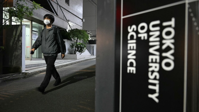 Une personne marche devant un panneau qui indique l'Université de Tokyo.