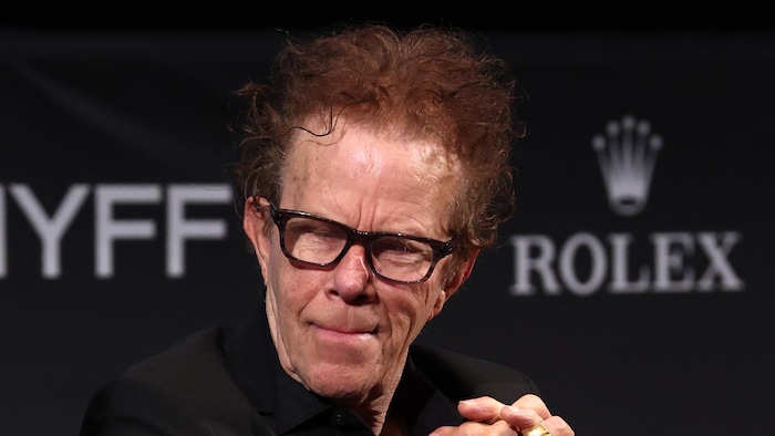 Tom Waits est assis pendant une conférence de presse. 