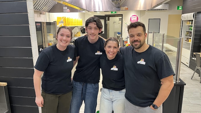 Tommy Garneau en compagnie d'employés se font prendre en photo dans un restaurant.