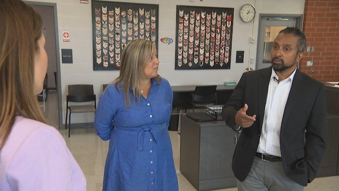 A man speaks to a woman in a school room.