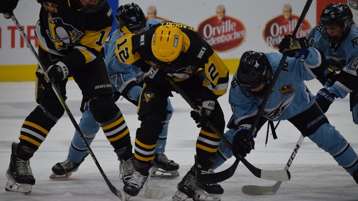 Des joueurs des deux équipes batailles pour la rondelle. 