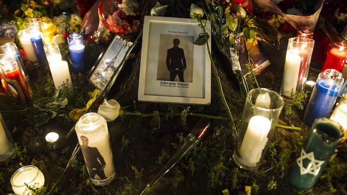 Des fleurs, une photo d’un rappeur et des lampions laissés sur un trottoir.