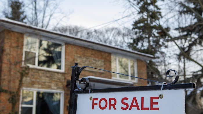 Une affiche « à vendre » devant une maison.

