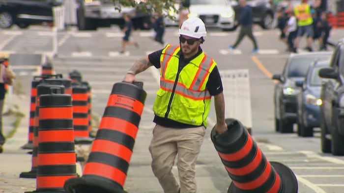Un travailleur place des cônes le long de la piste cyclable de la rue Bloor Ouest à Toronto, le 14 octobre 2026.