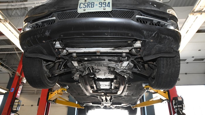 Vue du dessous d'une BMW montée sur un échafaudage en métal.