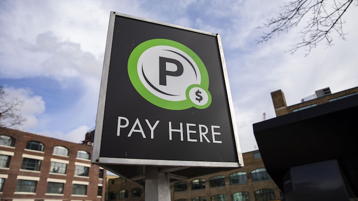 Une affiche dans un stationnement avec les mots « Payez ici ».
