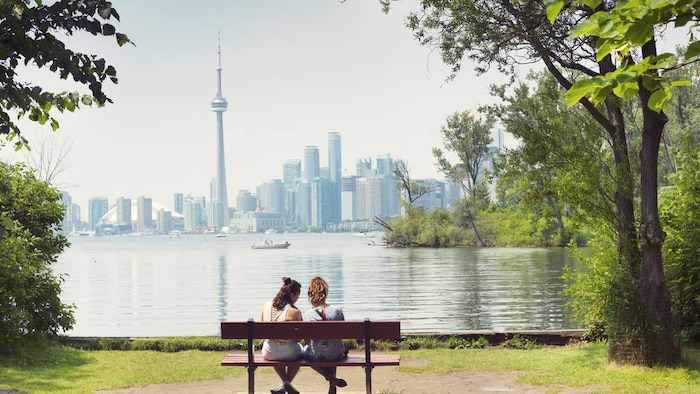 Deux femmes assises devant le lac Ontario, avec une vue de Toronto en arrière-plan.