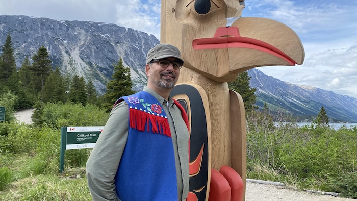 Sean McDougall à côté d'un mât totémique.